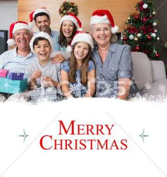 Composite image of extended family in christmas hats with gift boxes in living Stock Photos