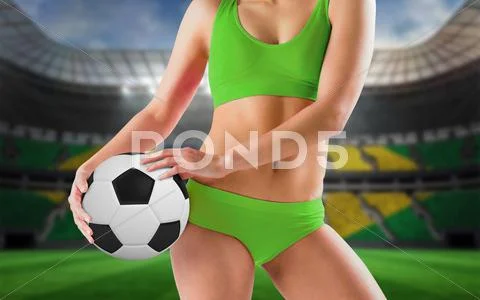 Composite image of fit girl in green bikini holding football Stock Photos