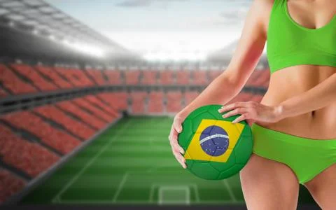 Composite image of fit girl in green bikini holding brasil ball Stock Photos