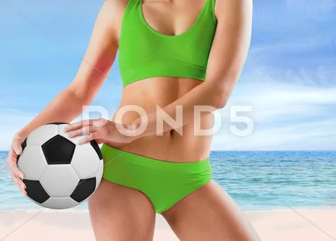 Composite image of fit girl in green bikini holding football Stock Photos