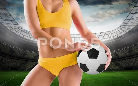 Composite image of fit girl in yellow bikini holding football Stock Photos