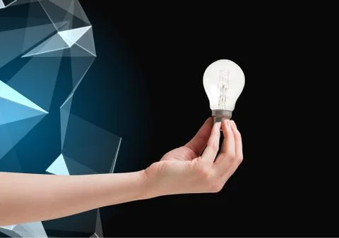 Composite image of Hand holding Lightbulb against graphic polygon in background 스톡 사진
