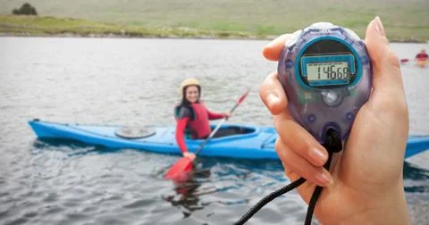 Composite image of a hand holding a timer against smiling woman in a kayak Stock Photos