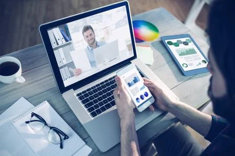 Composite image of handsome man working at his desk on laptop smiling at camera Stock Photos