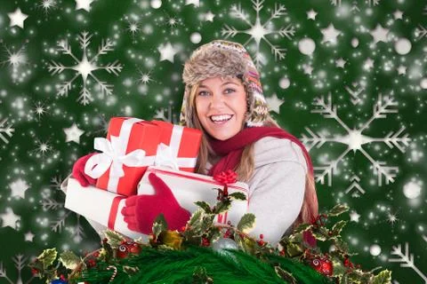 Composite image of happy blonde in winter clothes holding gifts Illustrazione stock