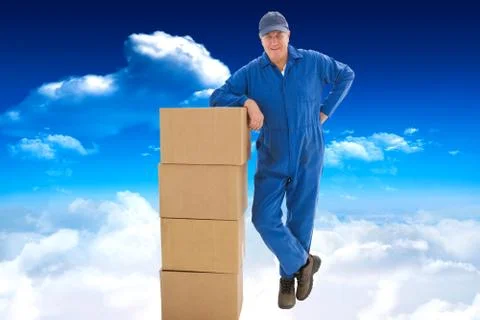 Composite image of happy delivery man leaning on pile of cardboard boxes Stock Photos