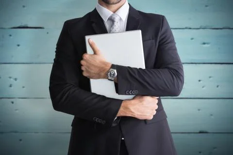 Composite image of mid section of businessman holding computer Fotos de archivo
