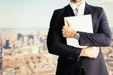 Composite image of mid section of businessman holding computer Fotos de archivo