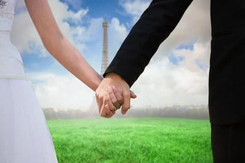 Composite image of mid section of newlywed couple holding hands in park Fotos Stock