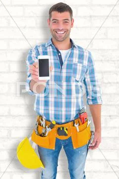 Composite image of portrait of smiling handyman showing mobile phone Stock Photos