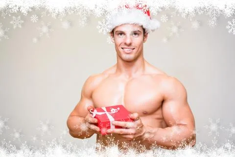 Composite image of shirtless macho man in santa hat holding gift Stock Illustration