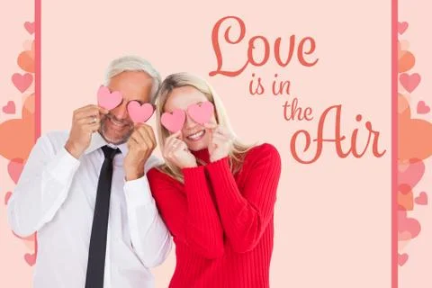 Composite image of silly couple holding hearts over their eyes Fotos Stock