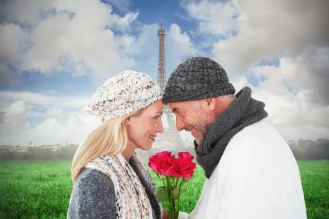 Composite image of smiling couple in winter fashion posing with roses Fotos Stock