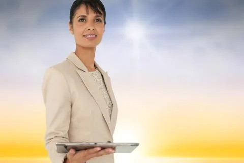 Composite image of woman using a tablet against sky background Foto stock
