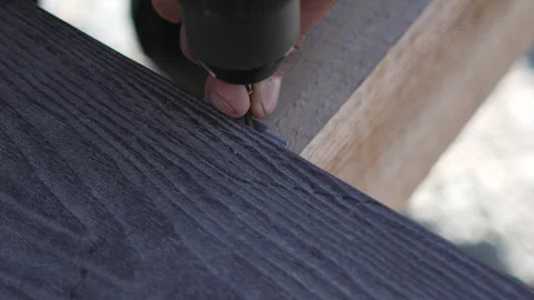 Composite Wood Deck hand screws into dark plank with drill outdoors Stock Footage 313196201