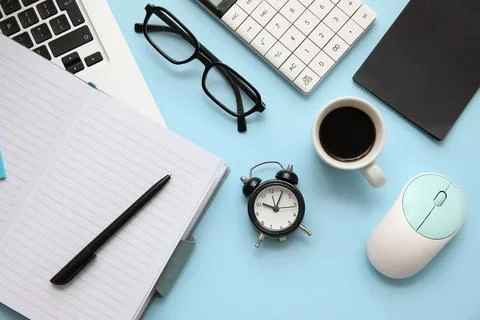 Composition with alarm clock, cup of coffee and modern laptop on blue backgro Stock Photos