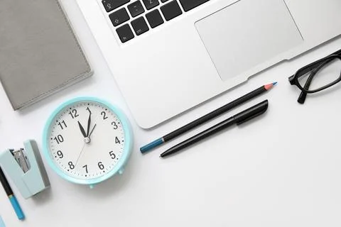 Composition with alarm clock, modern laptop and stationery on white backgroun Stock Photos