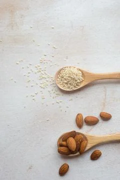 Composition of almonds and sesame seeds in wooden spoons. Stock Photos