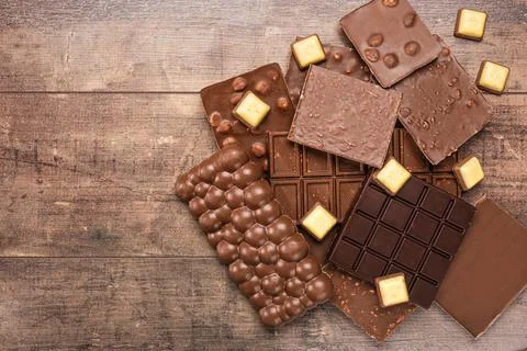 Composition bars and pieces of different milk and dark chocolate, on rustic w Stock Photos