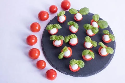Composition of basil, tomatoes and mozzarella on a stone black tile Stock Photos