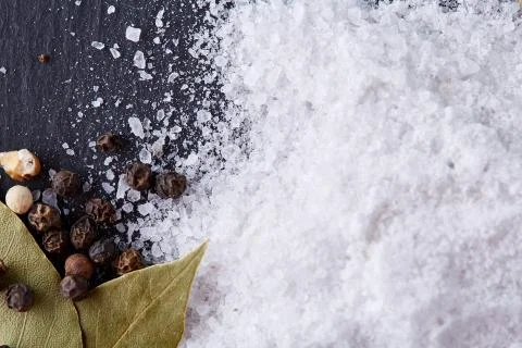 Composition of bay laurel leaf with peppercorn and salt isolated on dark Stock Photos