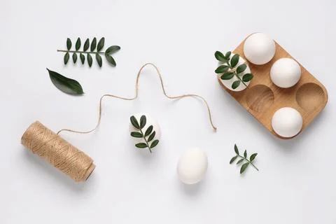Composition with beautiful Easter eggs, threads and green twigs isolated on w Stock Photos