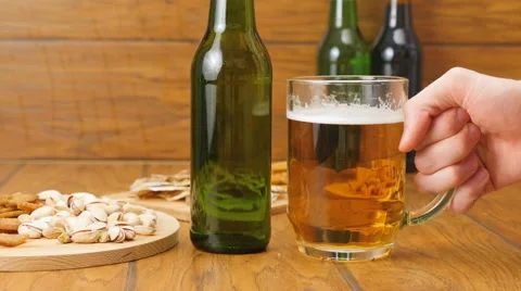 Composition of beer, crackers, pistachios, dried fish. A hand grabs a beer Stock Footage 67300687