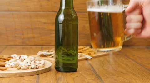 Composition of beer, crackers, pistachios, dried fish. A hand puts beer Stock Footage 67300689