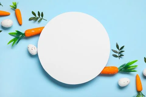 Composition with blank card, Easter eggs and green leaves on blue background Stock Photos