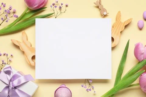 Composition with blank card, Easter eggs, gift box and flowers on beige backg Stock Photos