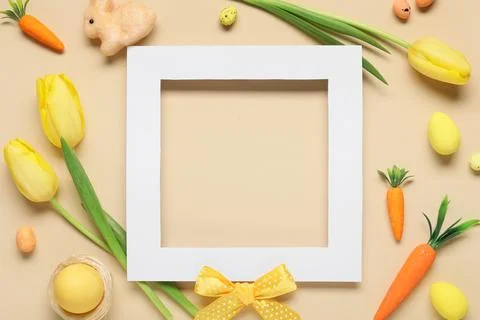 Composition with blank photo frame, Easter eggs and tulip flowers on beige ba Stock Photos