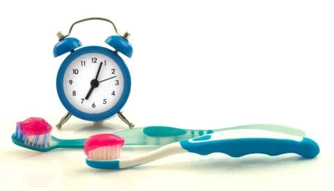 Composition from blue clock and toothbrushes with magenta toothpaste Stock Photos