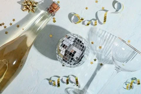 Composition with bottle of champagne, disco ball and confetti on blue grunge  Stock Photos