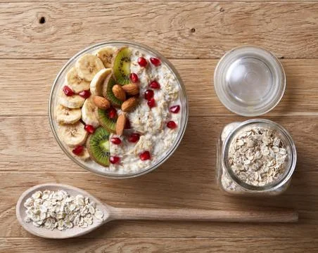 Composition with bowl of oatmeal porrige and dry oatmeal in glassware on wooden Stock Photos