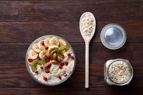 Composition with bowl of oatmeal porrige and dry oatmeal in glassware on wooden Stock Photos