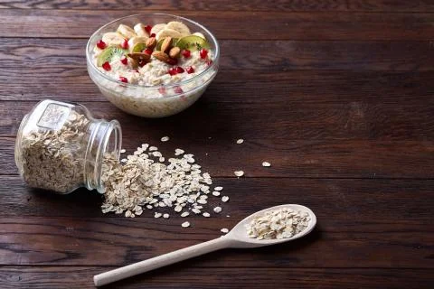 Composition with bowl of oatmeal porrige and dry oatmeal in glassware on vintage Stock Photos