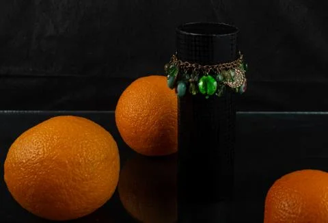 Composition of bracelet and three oranges on a dark background Stock Photos