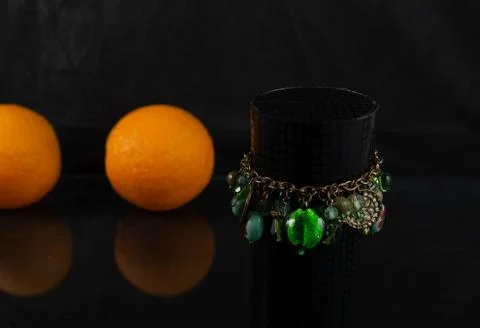 Composition of bracelet and three oranges on a dark background Stock Photos