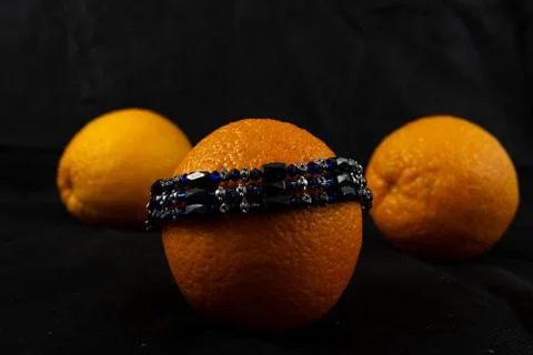 Composition of bracelet and three oranges on a dark background 스톡 사진