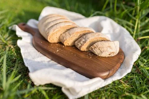 Composition of bread on wood board with white cloth napkin on the grass Stock Photos