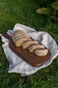 Composition of bread on wood board with white cloth napkin on the grass Stock Photos