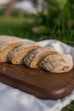 Composition of bread on wood board with white cloth napkin on the grass Stock Photos