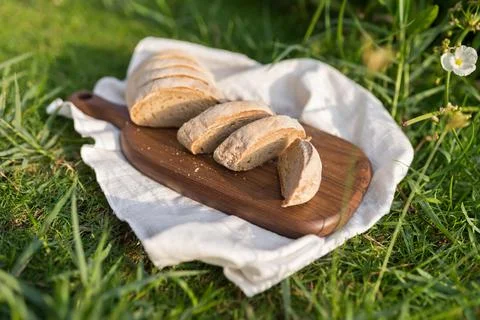 Composition of bread on wood board with white cloth napkin on the grass Stock Photos