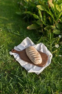 Composition of bread on wood board with white cloth napkin on the grass Stock Photos