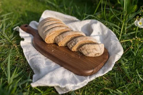 Composition of bread on wood board with white cloth napkin on the grass Stock Photos