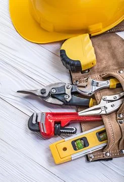 Composition of building tools in leather tool belt hard hat on wooden board Stock Photos