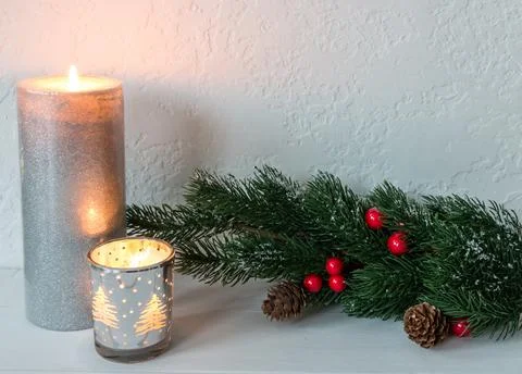 Composition of candles and tree branches decorated with snow, cones and red b Stock Photos
