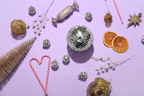 Composition with candy canes, disco balls and Christmas decor on lilac backgr Stock Photos