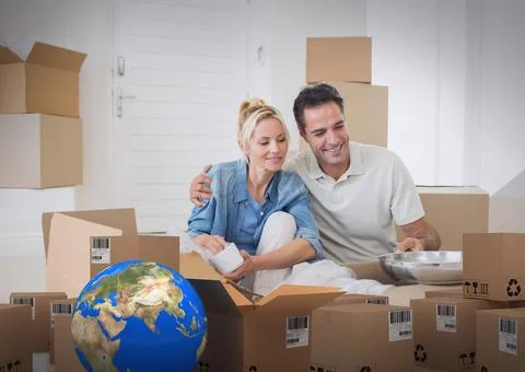 Composition of cardboard boxes with globe and couple unpacking in new home Stock Photos
