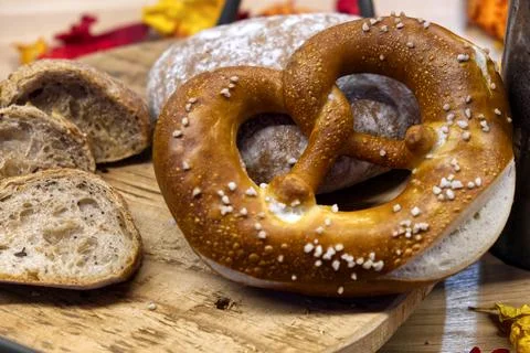 A composition of cereal bread and pretzels on a wooden cutting board Stock Photos